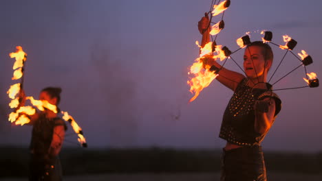 Frauen-Mit-Feuer-Bei-Sonnenuntergang-Auf-Dem-Sand-Tanzen-Und-Zeigen-Tricks-Vor-Dem-Wunderschönen-Himmel-In-Zeitlupe